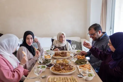 Un repas de famille pour l'Aïd el-Kebir : une grand-mère, des parents et des enfants partagent un festin copieux.