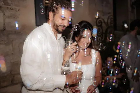 Un couple rayonnant trinque entouré de bulles, célébrant leur mariage civil à la mairie.