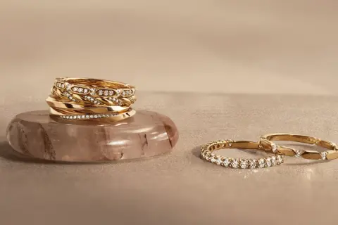 Pile d'alliances en or et diamants sur une pierre, et deux autres bagues serties de diamants. Comment choisir son alliance ?