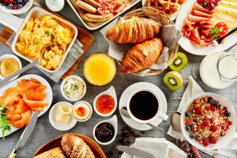 Un festin pour un brunch mariage : œufs brouillés, saumon fumé, croissants, fruits, café et jus d'orange.
