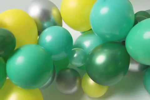 Grappe de ballons verts, jaunes et argentés. Idéal pour apprendre comment attacher des ballons en grappe pour une décoration festive.