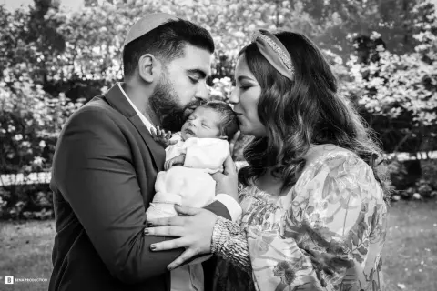 Un couple juif célèbre la circoncision de leur bébé, entourés d'amour et de tendresse.