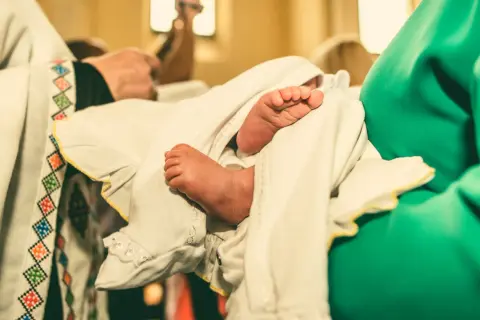 Les petits pieds d'un bébé enveloppé dans un linge blanc lors d'un baptême protestant.