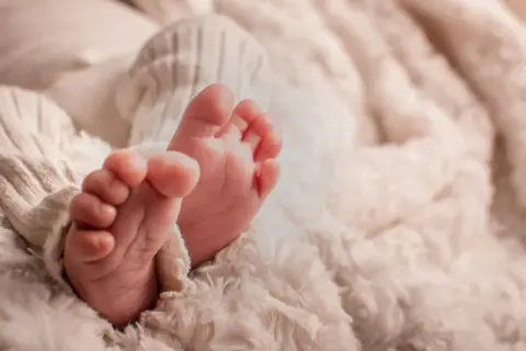 Petits pieds de bébé, tendrement enveloppés dans une couverture douce. Une image symbolisant la pureté et le début d'une nouvelle vie, peut-être en attente de la circoncision islam 7 jours.