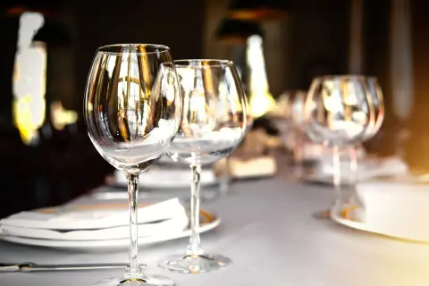 Trois verres à vin vides sur une table dressée, prêts pour un repas. Chaque verre reflète la lumière, comme un marque place verre.