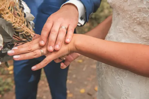 Mains jointes, alliances étincelantes, bouquet de mariée. Un moment clé parmi les plus belles demandes en mariage.