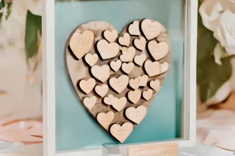 Livre d'or mariage coeur en bois, rempli de petits cœurs gravés de noms, un souvenir précieux des vœux échangés.