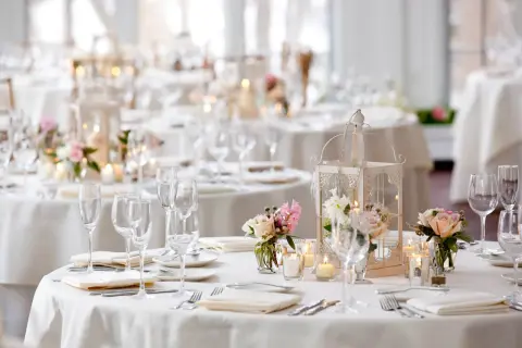 Disposition table mariage élégante avec lanternes, bougies et bouquets de roses. Vaisselle et verres prêts pour les invités.