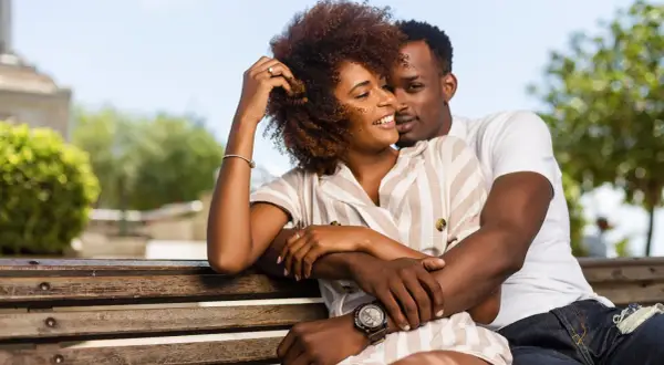 Un couple s'enlacent tendrement sur un banc, un moment de complicité qui évoque la prière des époux pour leur mariage.