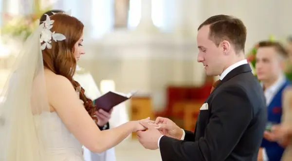 Le marié passe la bague à la mariée lors de leur mariage à l'église.