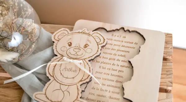 Ours en bois gravé avec le prénom Arthur, à côté d'une sphère en verre remplie de fleurs séchées.
