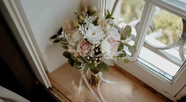 Un bouquet de mariage pastel avec des roses, des lisianthus et des herbes de la pampa. Une belle inspiration pour votre liste des fleurs pour mariage.
