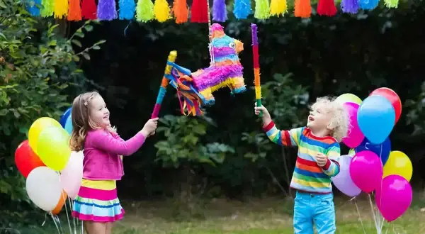 Des enfants joyeux s'amusent à casser une pinata colorée, une scène parfaite pour apprendre comment accrocher une pinata pour une fête.