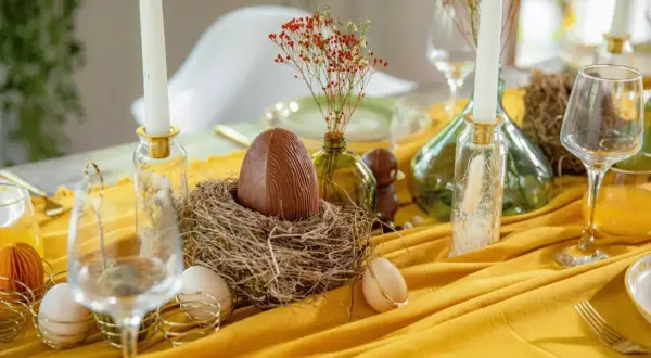 Un grand œuf en chocolat dans un nid, entouré d'œufs et de bougies, pour un joyeux dimanche de Pâques.