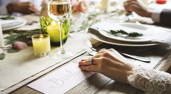 Un verre de champagne et une bougie illuminent une table dressée pour un mariage. La carte "Bride" annonce le cocktail de bienvenue.