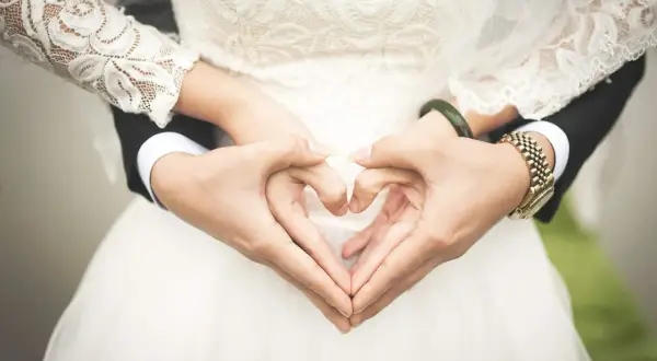 Les mains du jeune marié et de sa mariée forment un cœur sur la robe de mariée.