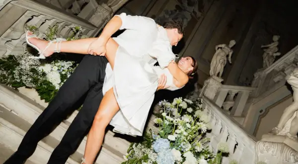 Un couple s'embrasse passionnément sur un escalier orné de fleurs, célébrant leur jour du mariage.