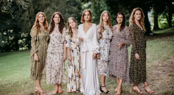 Six femmes en robes fleuries et une en blanc, probablement les témoins d'un mariage.