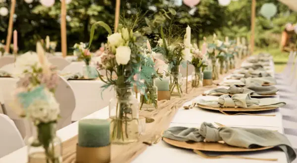 Décoration de chaise de mariage fait maison : table dressée avec des fleurs, des bougies et des serviettes en tissu nouées.