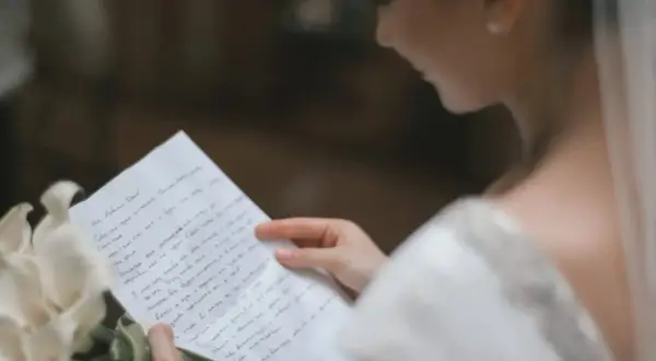 Une mariée lit une lettre d'intention mariage, un bouquet de callas à ses côtés.