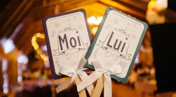 Deux pancartes "Moi" et "Lui" ornées de cœurs et d'oiseaux, parfaites pour le top des jeux de mariage.