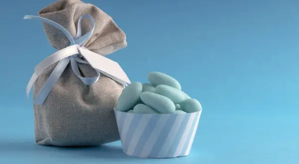 Un sachet de dragées bleues, parfait pour un thème baptême garçon, avec une petite coupelle rayée.