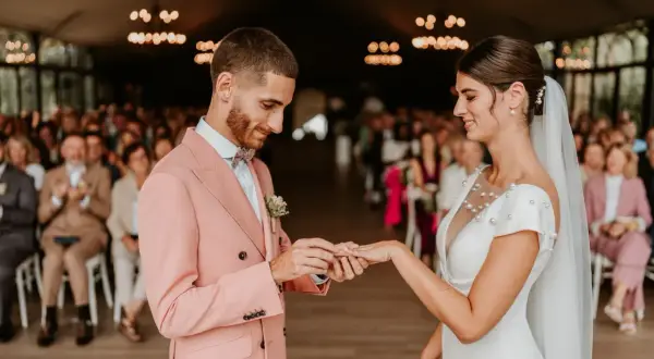 Mariage : le marié met la bague à la mariée. Comment choisir son photographe de mariage pour immortaliser ce moment ?