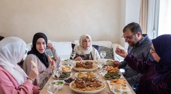 Un repas de famille pour l'Aïd el-Kebir : une grand-mère, des parents et des enfants partagent un festin copieux.