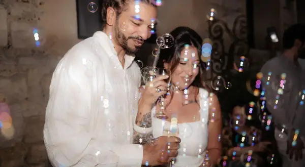 Un couple rayonnant trinque entouré de bulles, célébrant leur mariage civil à la mairie.