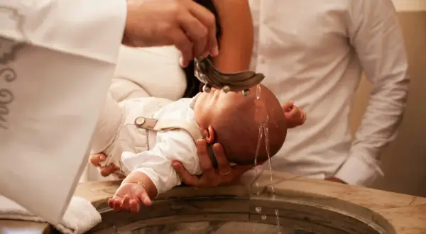 Cérémonie de baptême : l'eau bénite coule sur la tête du bébé. Une douce chanson de baptême accompagne ce moment sacré.