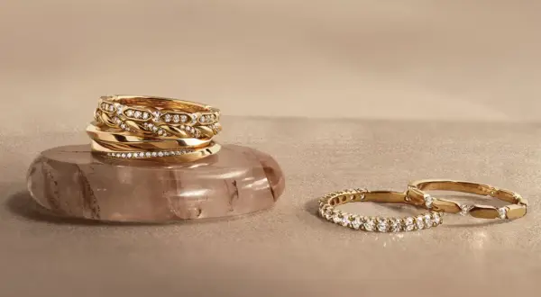 Pile d'alliances en or et diamants sur une pierre, et deux autres bagues serties de diamants. Comment choisir son alliance ?