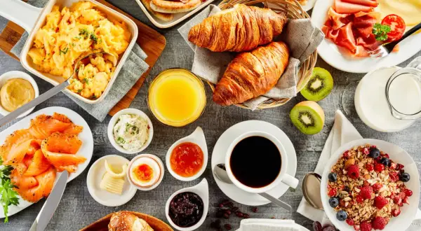 Un festin pour un brunch mariage : œufs brouillés, saumon fumé, croissants, fruits, café et jus d'orange.