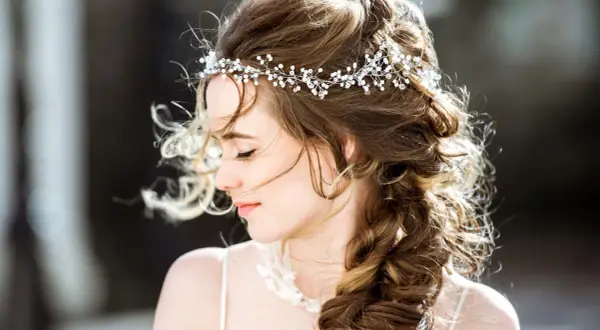 Une jeune femme avec une coiffure bohème, ornée d'une tiare scintillante, ses cheveux ondulés tombant en tresse.