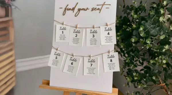 Un panneau "Trouvez votre siège" avec des cartes de table numérotées, chacune avec des noms d'invités. Un marque place vierge est visible sur la carte de la table 8.