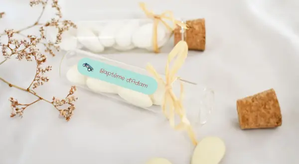 Des dragées pour créer une liste de baptême, dans des fioles décorées d'une petite voiture et du nom "Adam".