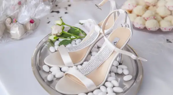 Escarpins blancs ornés de strass, entourés de dragées. Une question se pose : combien de dragées par personne pour un tel événement ?