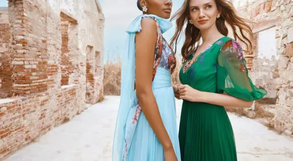 Deux femmes élégantes posent devant des ruines. L'une porte une robe bleu ciel plissée, l'autre une robe verte. Idées pour comment s'habiller pour un mariage.