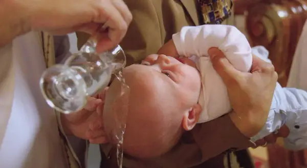 Un bébé est baptisé, l'eau bénite coule sur sa tête. Un moment solennel pour comprendre pourquoi baptiser son enfant.