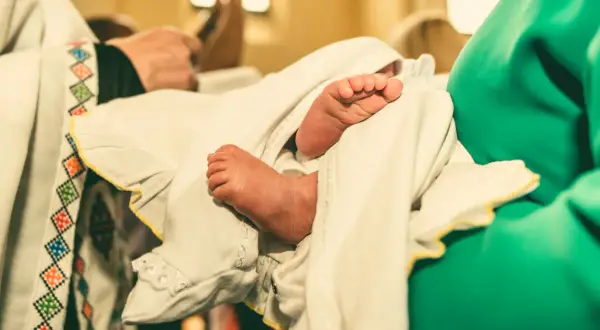 Les petits pieds d'un bébé enveloppé dans un linge blanc lors d'un baptême protestant.