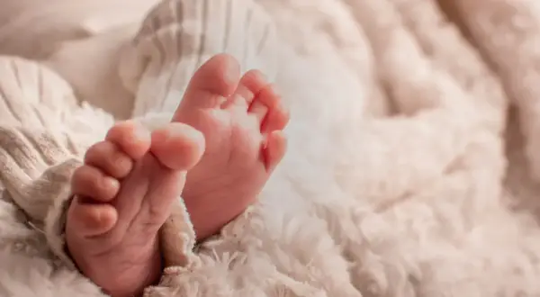 Petits pieds de bébé, tendrement enveloppés dans une couverture douce. Une image symbolisant la pureté et le début d'une nouvelle vie, peut-être en attente de la circoncision islam 7 jours.