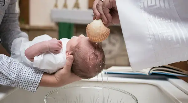 Cérémonie de baptême à l'église. L'eau bénite coule sur la tête du bébé, un moment sacré qui marque le début de sa vie spirituelle. La durée de ce baptême est courte mais pleine de sens.