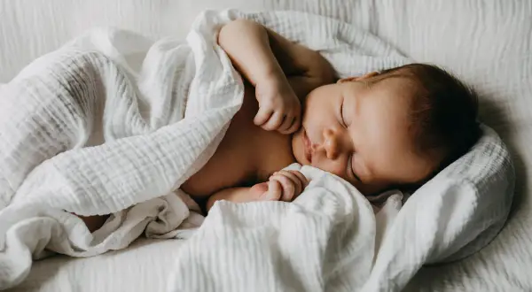 Un doux bébé endormi, parfait pour un texte félicitations naissance garçon. Un petit trésor emmailloté dans une couverture blanche.