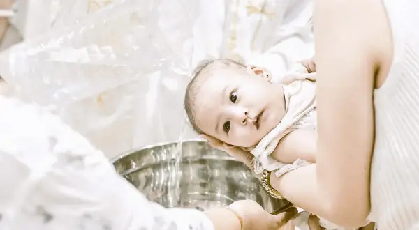 Bébé se fait baptiser sans catéchisme, l'eau bénite coule dans la cuve.
