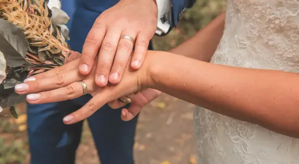 Mains jointes, alliances étincelantes, bouquet de mariée. Un moment clé parmi les plus belles demandes en mariage.
