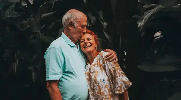 Un couple âgé s'embrasse tendrement, un moment de joie pour fêter sa retraite en famille.