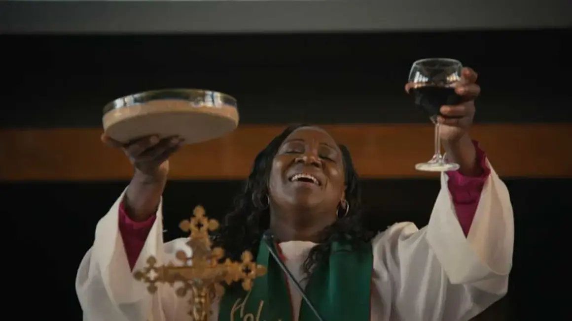 Une femme, peut-être une marraine de substitution, célèbre la communion en levant une coupe de vin et une patène.