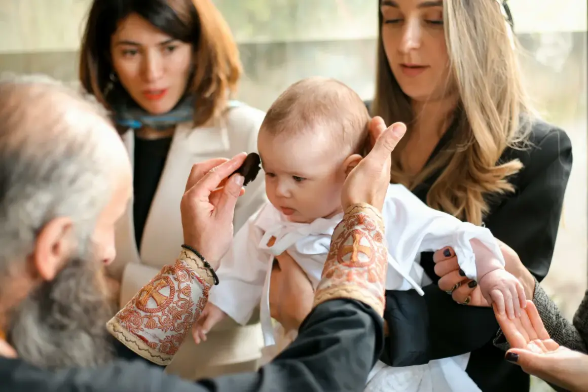 Cérémonie religieuse : un bébé est tenu par sa marraine. Le prêtre applique une onction. Peut-on changer de marraine ?