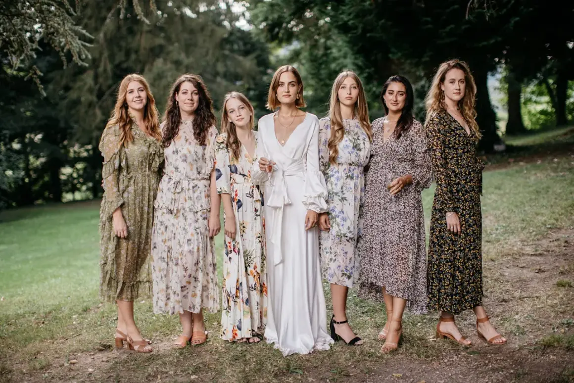Six femmes en robes fleuries et une en blanc, probablement les témoins d'un mariage.
