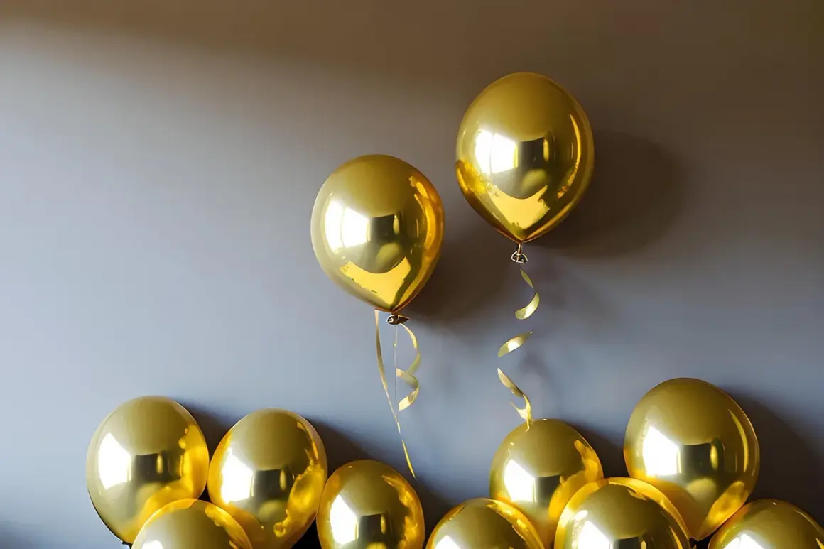 Des ballons dorés brillants flottent près d'un mur. Une astuce pour savoir comment faire tenir des ballons au plafond : utilisez du ruban adhésif double face.