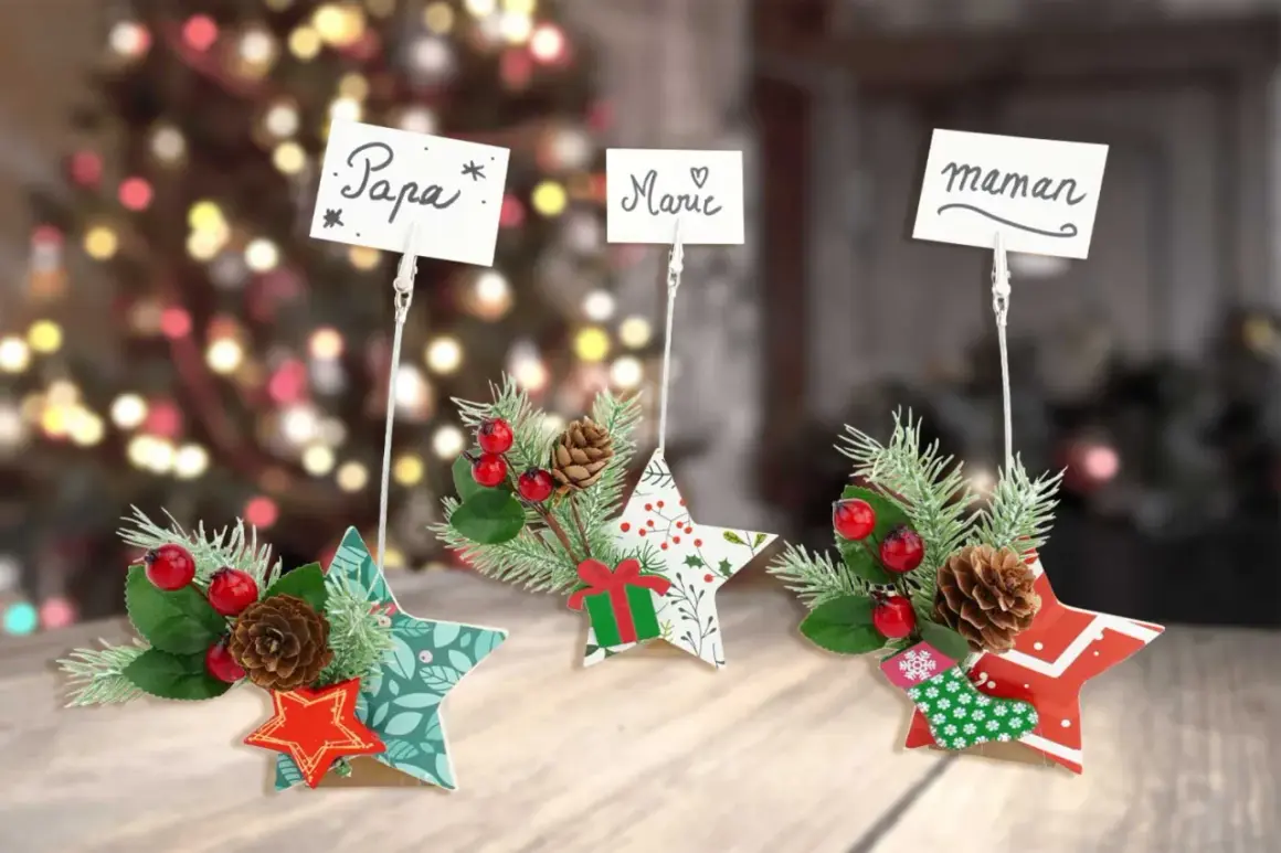 Trois étoiles décoratives de Noël, ornées de branches de sapin, de baies rouges et de pommes de pin, servent d'étiquette marque place pour "Papa", "Marie" et "Maman".